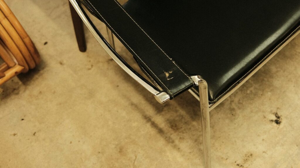 a black leather chair sitting next to a wooden chair